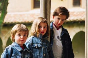 Three children standing together in a stone courtyard
